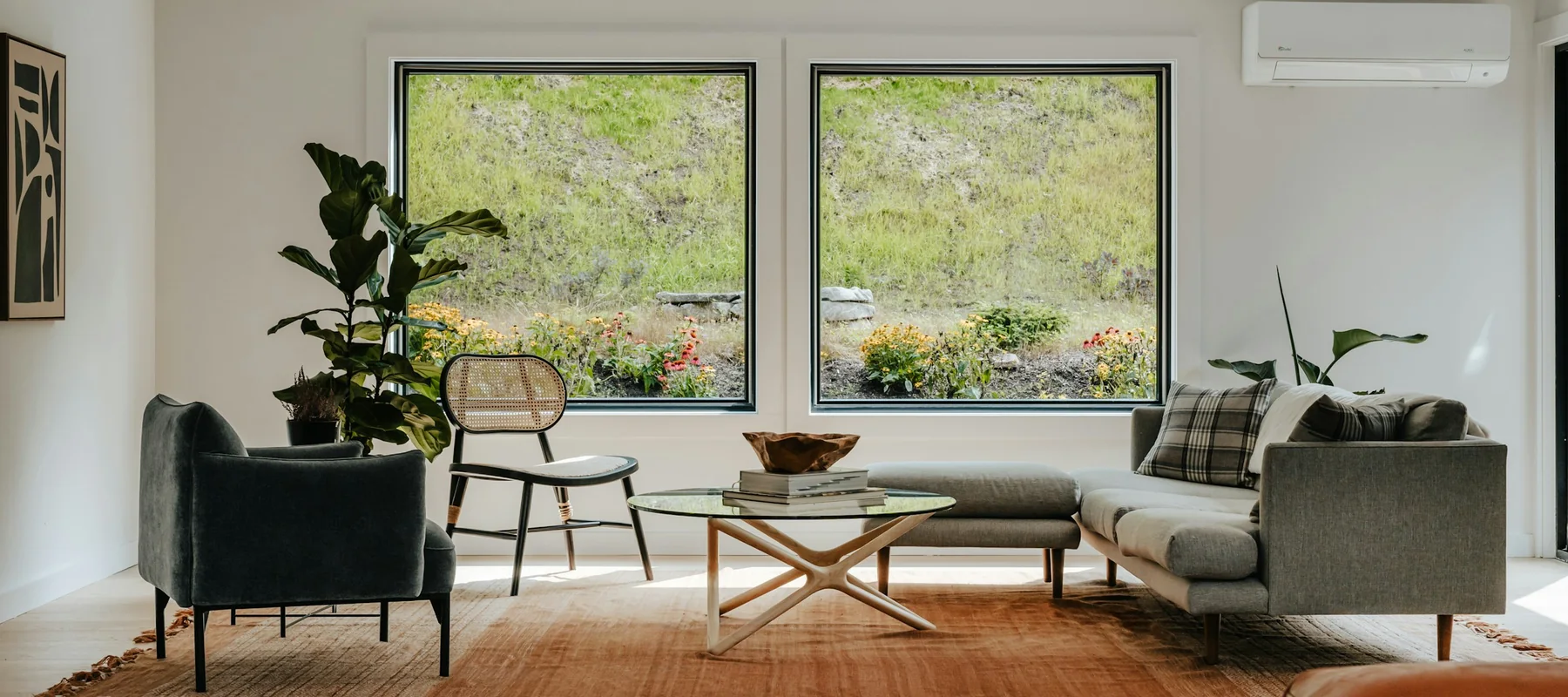 Welcoming living room with large windows, a grey sofa and natural wood furniture
